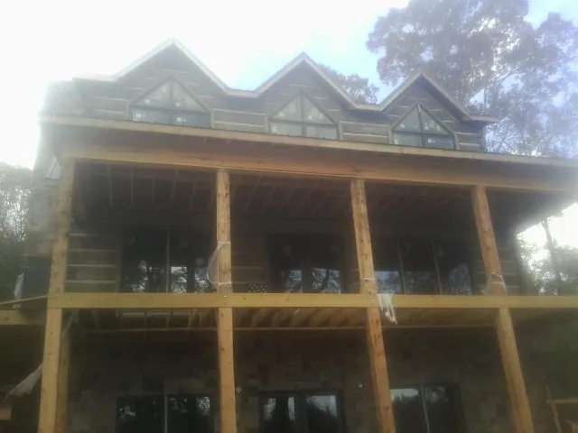 Dormers and porch framing on a large log home under construction — Roof Coating work by our crew in North Reading